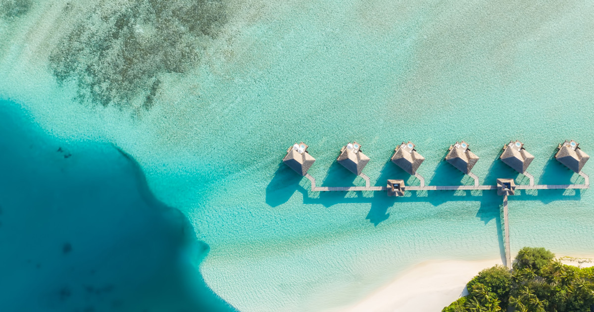 Aerial view of a pristine white sandbank surrounded by luminous turquoise lagoon