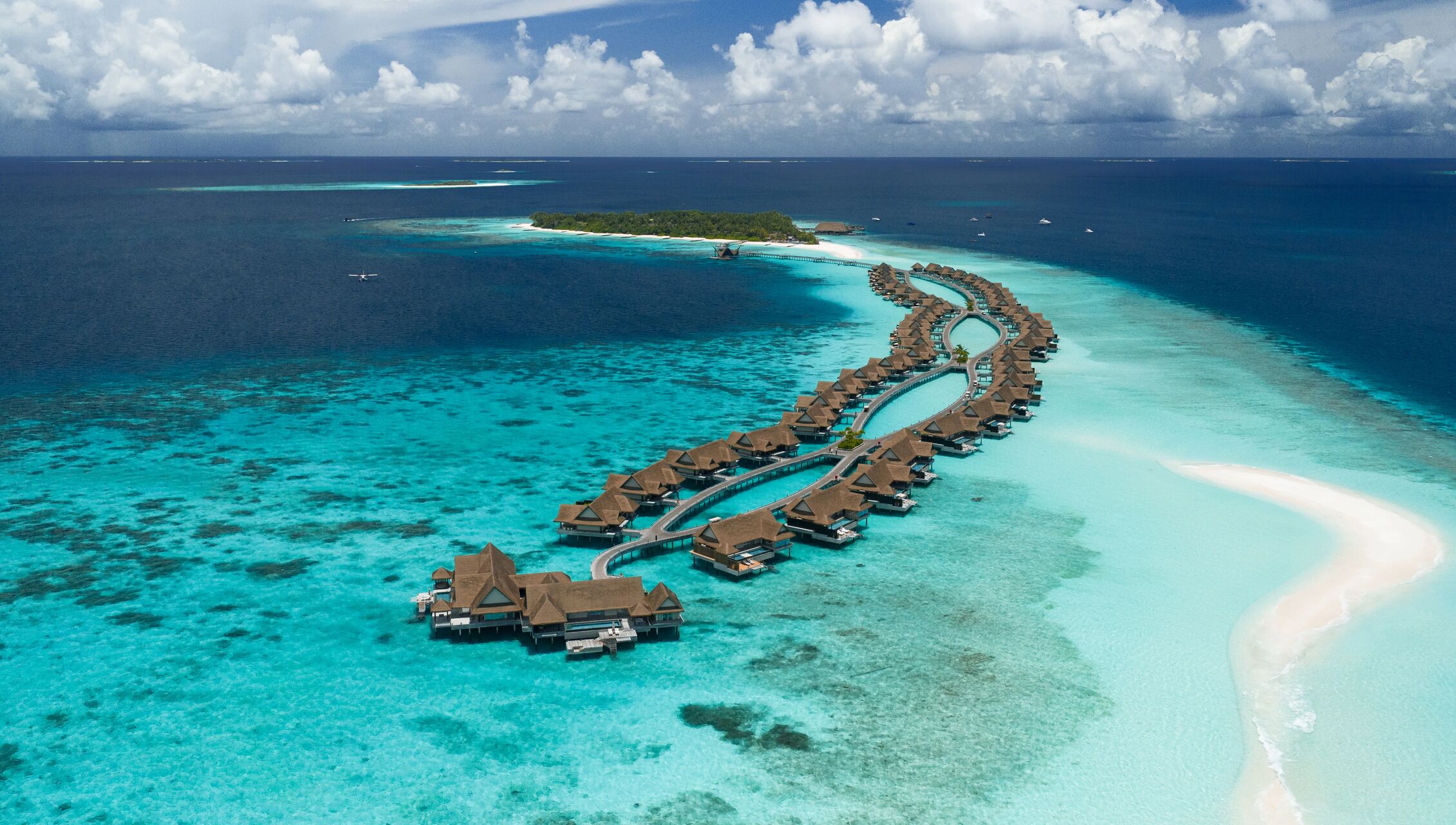 Aerial view of JOALI Maldives overwater villas and distinctive jetty architecture in Raa Atoll